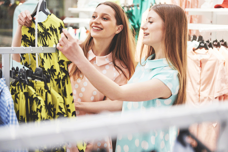 raparigas a ver roupa em loja para trocar por cupões de descontos pela roupa usada