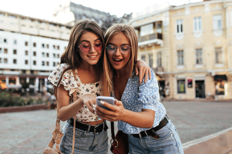 duas amigas a verem aplicações de moda ao ar livre